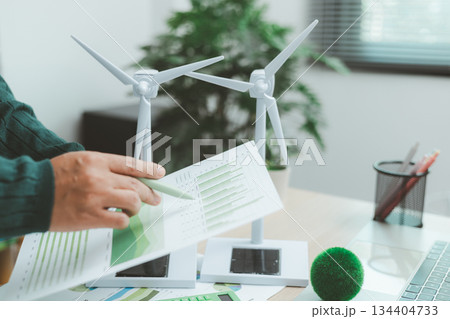 Eco-friendly business concept with hand analyzing financial charts and green earth globe symbolizing sustainable investment, environmental data analysis and green economy growth. green business. Eco-friendly business concept with hand analyzing financial charts and green earth globe symbolizing sustainable investment, environmental data analysis and green economy growth. green business. 134404733