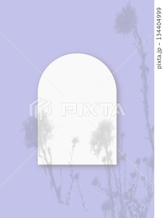 Natural light casts shadows from wildflowers on an arched sheet of white paper lying on a vertical purple background. Mockup 134404999