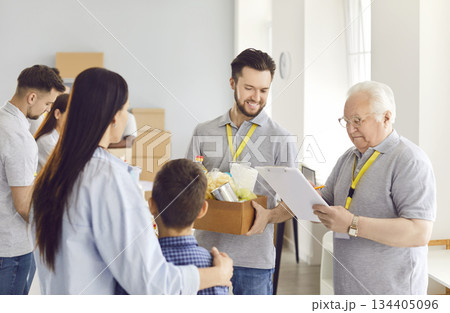 Volunteers giving free food donations for people in need in charitable foundation. Volunteers giving free food donations for people in need in charitable foundation. 134405096