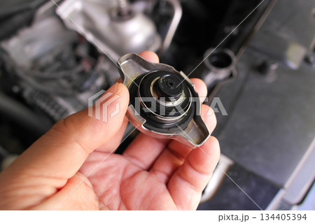 A hand holding a car radiator cap A hand holding a car radiator cap 134405394