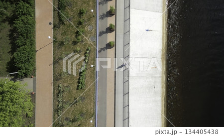 People walking along riverbank in urban park. Clip 134405438