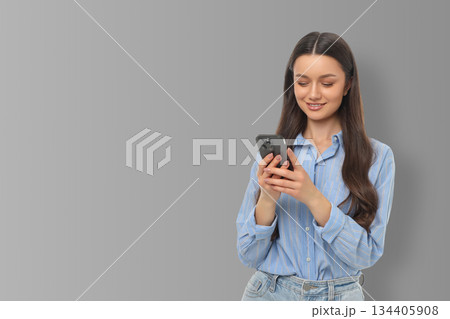 Woman checks messages on her smartphone with a smile 134405908