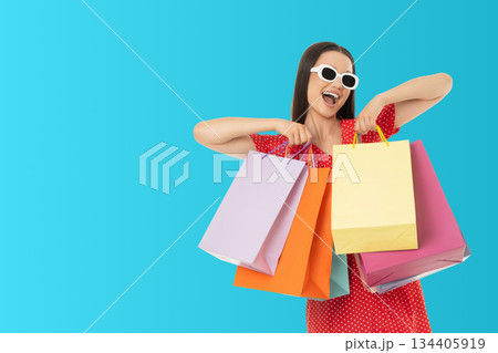 Woman holds colorful shopping bags while smiling at the camera Woman holds colorful shopping bags while smiling at the camera 134405919