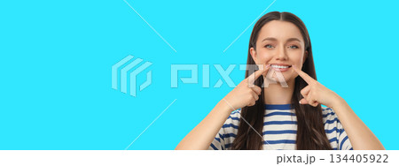 Woman points at her smile on a bright blue backdrop 134405922