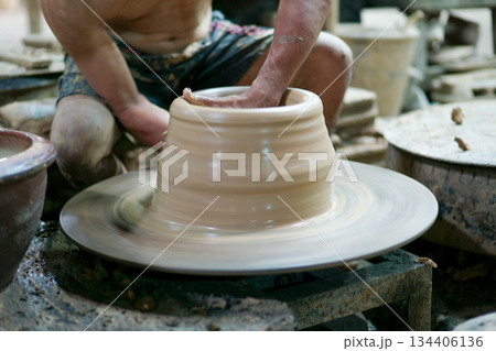 Selective focus on the clay work on the spinning tray with hands of worker Selective focus on the clay work on the spinning tray with hands of worker 134406136