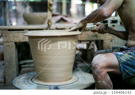 Selective focus on the clay work on the spinning tray with hands of worker 134406142