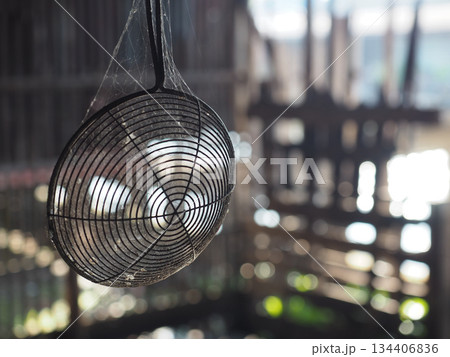 Old wire strainer spiderweb dust rustic kitchen metal utensil soft sunlight bokeh background vintage mood hanging 134406836