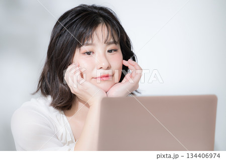 ノートパソコンを見る若いかわいい女性リラックスした嬉しい楽しい資格や勉強などの春色ピンクのイメージ ノートパソコンを見る若いかわいい女性リラックスした嬉しい楽しい資格や勉強などの春色ピンクのイメージ 134406974