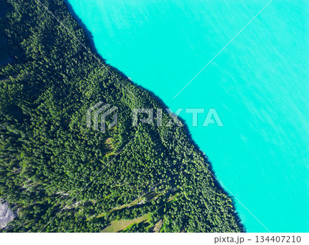 空撮で見た、森林とエメラルドグリーンの湖の境界線 134407210