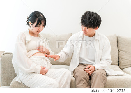 マイホームのリビングソファーで妊婦のお腹を触る男性(家族・パパ) マイホームのリビングソファーで妊婦のお腹を触る男性(家族・パパ) 134407524