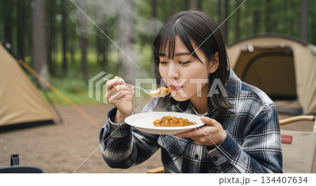 キャンプ場でカレーライスを食べる女性 134407634