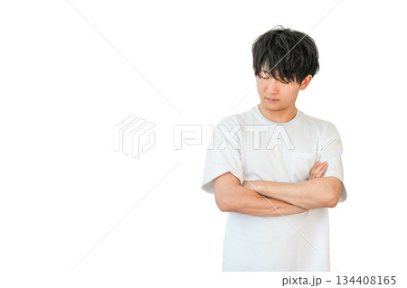 腕組みをして考えるTシャツ姿の若いアジア人男性（悩み,悩む,検討,困る） 134408165