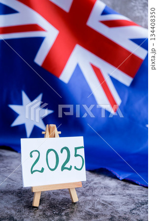 Australian flag and text 2025 trendy template for upcoming year campaigns. Patriotic design marking 2025 beside national flag. Concept of future vision and planning ideal for annual report or goal 134408350