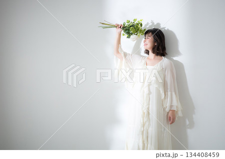 白背景で花束を持つ若い女性のナチュラルな笑顔と透明感 結婚式前撮りやボタニカルなどのイメージ 134408459