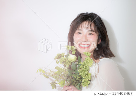 白背景で花束を持つ若い女性のナチュラルな笑顔と透明感 結婚式前撮りやボタニカルなどの幸せいっぱい 134408467