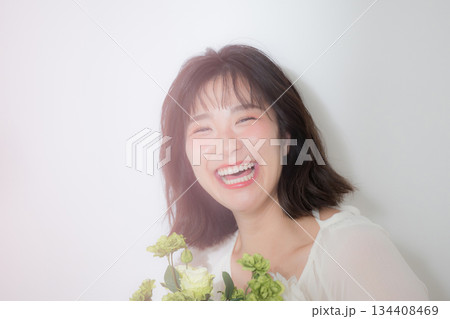 白背景で花束を持つ若い女性のナチュラルな笑顔と透明感 結婚式前撮りやボタニカルなどの幸せいっぱい 134408469