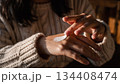 白いニットを着てハンドクリームで手肌をケアする女性 134408474