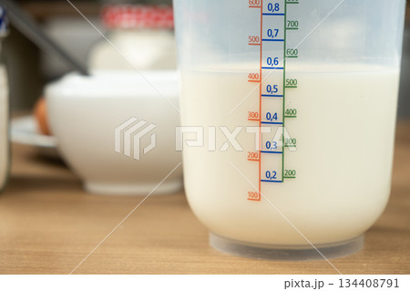 Fresh White Milk in a Plastic Measuring Cup with Scale Markings. Fresh White Milk in a Plastic Measuring Cup with Scale Markings. 134408791