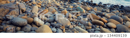 Deserted rocky pebble beach. Abstract nature pebbles background. Pebbles texture. Stone beach. Horizontal banner 134409139