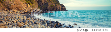 Deserted rocky pebble beach with clear blue water Deserted rocky pebble beach with clear blue water 134409140
