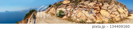 Panoramic view of the Mediterranean coast of Spain. Seascape with a rocky path around a mountain. High mountain road. Morro de Toix viewpoint. Calpe, Alicante, Spain 134409160