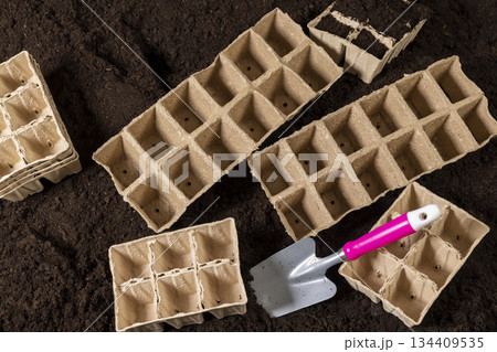 empty cardboard pots for seedlings scattered in a field with fertile brown soil, soil mixed with humus and peat, and paper disposable cups for seedlings in spring empty cardboard pots for seedlings scattered in a field with fertile brown soil, soil mixed with humus and peat, and paper disposable cups for seedlings in spring 134409535