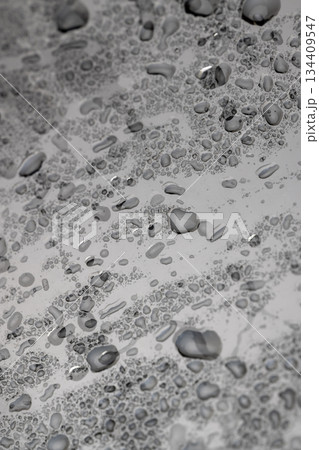 a whole wet old glass lies on a black slate board with an uneven texture, a whole sheet of transparent glass used in construction covered with water droplets 134409547