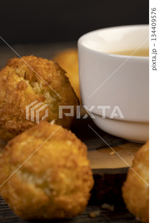 sweet cookies with coconut pieces are on the table, a group of sweet freshly made cookies for a tea party, a white cup filled with hot tea 134409576