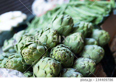 Pile of artichokes displayed on market counter 134409786