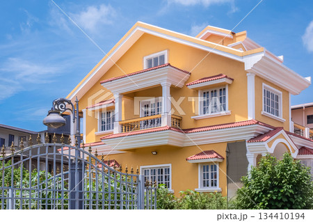 Exterior of a yellow two-storey house with classical facade and front garden Exterior of a yellow two-storey house with classical facade and front garden 134410194