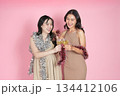 New Year celebration. Two young women toasting with drinks while adorned in festive decorations. 134412106