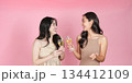 Celebration. Two young women toasting with champagne glasses against a pink background. 134412109