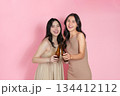 Cheers Two young women celebrating with beer bottles against a pink background. 134412112