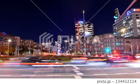 Warsaw, Poland. 4 November 2025. City life after dark. Traffic with cars passing on the street in center city in the night. Lights street and buildings towering around them. Warsaw, Poland. 4 November 2025. City life after dark. Traffic with cars passing on the street in center city in the night. Lights street and buildings towering around them. 134412114