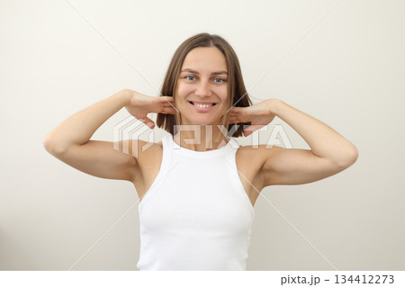 Happy young woman with flying hair smiling at camera on white backdrop. Casual natural look, raised arms, carefree emotion. Concept of freedom, fun, energy, youth branding, wellness, personal care Happy young woman with flying hair smiling at camera on white backdrop. Casual natural look, raised arms, carefree emotion. Concept of freedom, fun, energy, youth branding, wellness, personal care 134412273