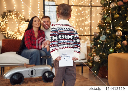 Dear Santa, boy is holding letter. Happy family celebrating new year together at home Dear Santa, boy is holding letter. Happy family celebrating new year together at home 134412529