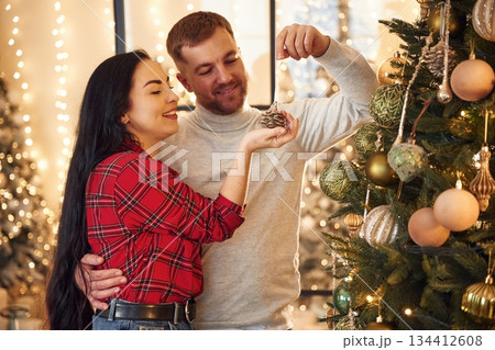 They decorate the Christmas tree. Couple is celebrating new year indoors together 134412608