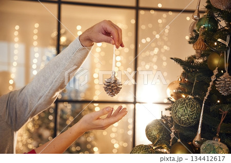 Taking care of new year decoration. Close up view of man's and woman's hands 134412617