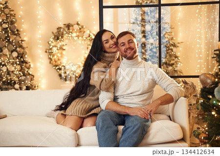 Sitting and smiling. Couple is celebrating new year indoors together 134412634