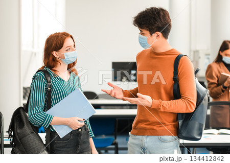 Healthcare, Education, Lifestyle And People Concept. Group of diverse international students wearing protective medical masks and talking, asian guy and redhead woman standing with backpacks 134412842