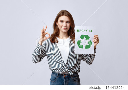 Smiling Young Lady Holding Motivational Placard With Recycle Sign And Showing Ok Gesture, Agitating To Save Ecology And Nature With Zero Waste Concept, Standing Over Grey Studio Background, Free Space Smiling Young Lady Holding Motivational Placard With Recycle Sign And Showing Ok Gesture, Agitating To Save Ecology And Nature With Zero Waste Concept, Standing Over Grey Studio Background, Free Space 134412924