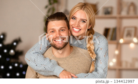 Joyful man and woman cuddling at home during xmas eve, smiling at camera, free space Joyful man and woman cuddling at home during xmas eve, smiling at camera, free space 134412997
