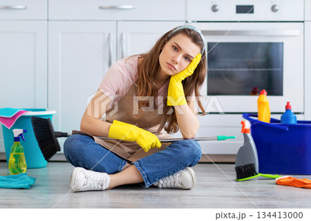 Depressed millennial housewife tired from domestic chores, sitting on kitchen floor surrounded by cleaning supplies. Exhausted young lady sick of household duties, taking break Depressed millennial housewife tired from domestic chores, sitting on kitchen floor surrounded by cleaning supplies. Exhausted young lady sick of household duties, taking break 134413000