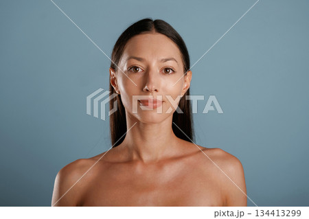 Front view, portrait. Young woman is in the studio against background 134413299