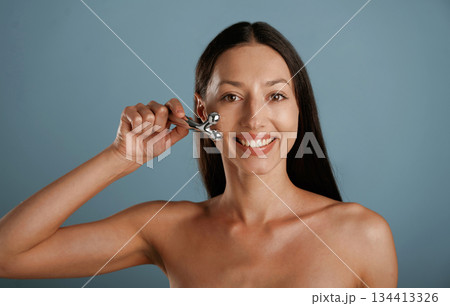 Skin massager. Young woman is in the studio against background Skin massager. Young woman is in the studio against background 134413326