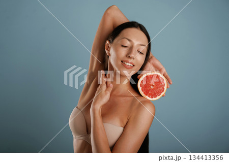 Grapefruit, conception of healthy eating. Young woman is in the studio against background 134413356
