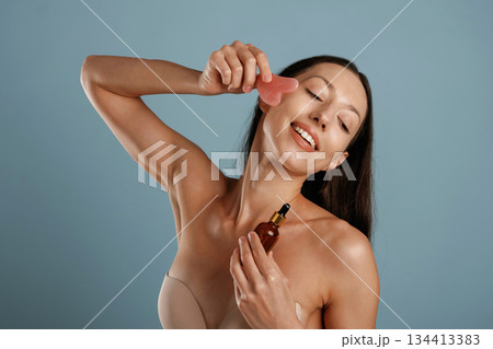 Facial skin care. Young woman is in the studio against background Facial skin care. Young woman is in the studio against background 134413383