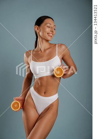 Skinny body, diet conception, with oranges. Young woman is in the studio against background Skinny body, diet conception, with oranges. Young woman is in the studio against background 134413521