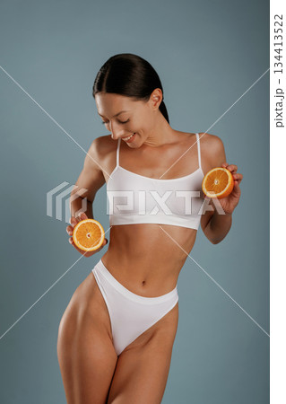 Skinny body, diet conception, with oranges. Young woman is in the studio against background 134413522