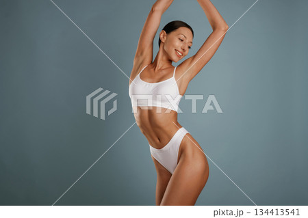 Fitness model is in white underwear. Young woman is in the studio against background 134413541